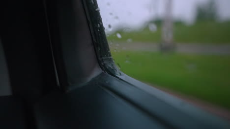 gotas de agua ondulan y brillan en la esquina de la ventana de un auto mientras el auto conduce