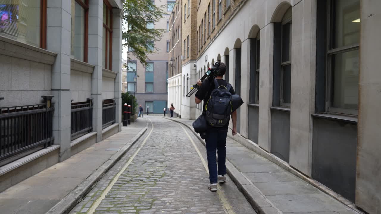 Videograf går ned ad en bygade på vej til en filmoptagelse.
