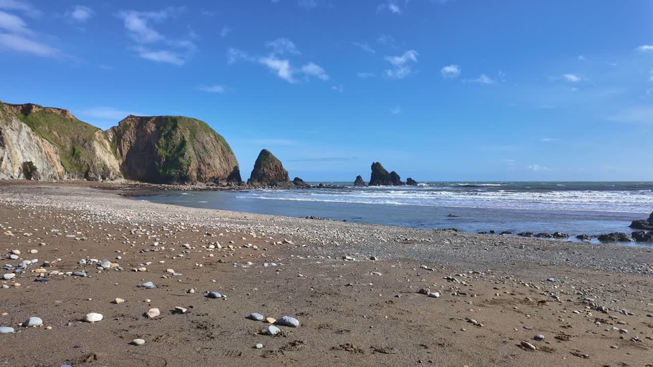 Selang waktu pantai berpasir kerikil, ombak lembut, dan laut tenang di laguna Copper Coast Waterford Irlandia di musim semi