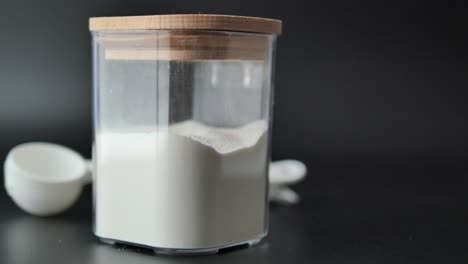 flour in a clear container with measuring cups