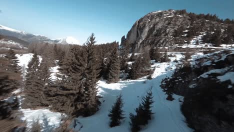 FPV-diving-shot-down-the-side-of-the-mountain-flying-between-trees