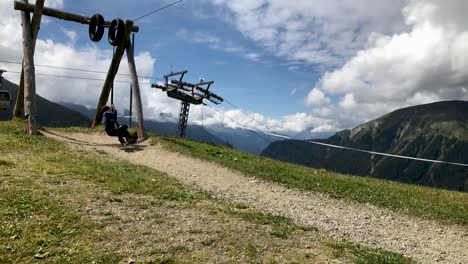 cute young boy swinging in slow motion on top of a mountain