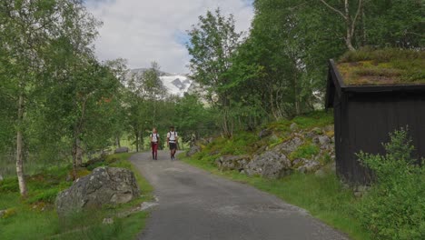 hikers on a scenic mountain path with a glacier and traditional hut