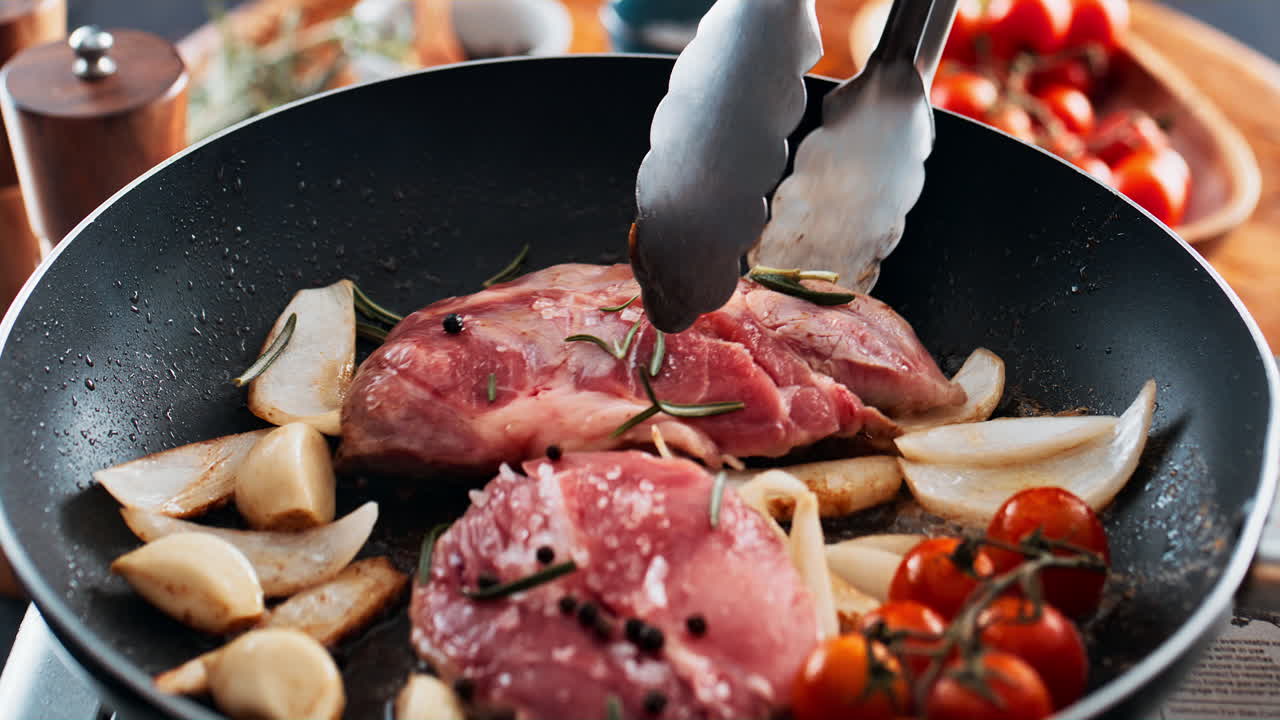 Cooking steak with garlic and tomatoes in a pan