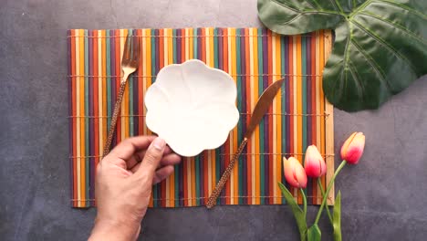 empty plate, utensils and floral arrangement on a colorful placemat