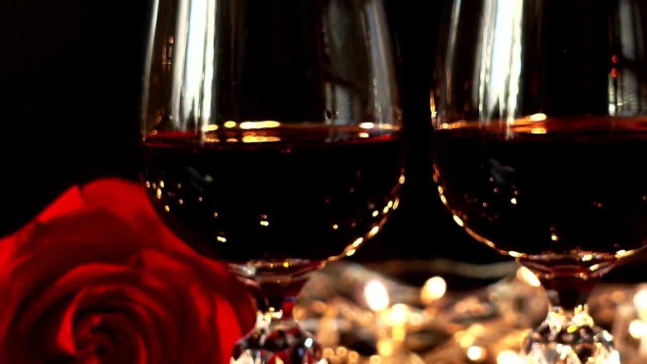 Taças de vinho e rosa contra o fundo de guirlandas brilhantes