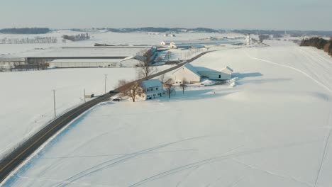 aerial of farm buildings and fields covered in white winter snow in united states of america, usa