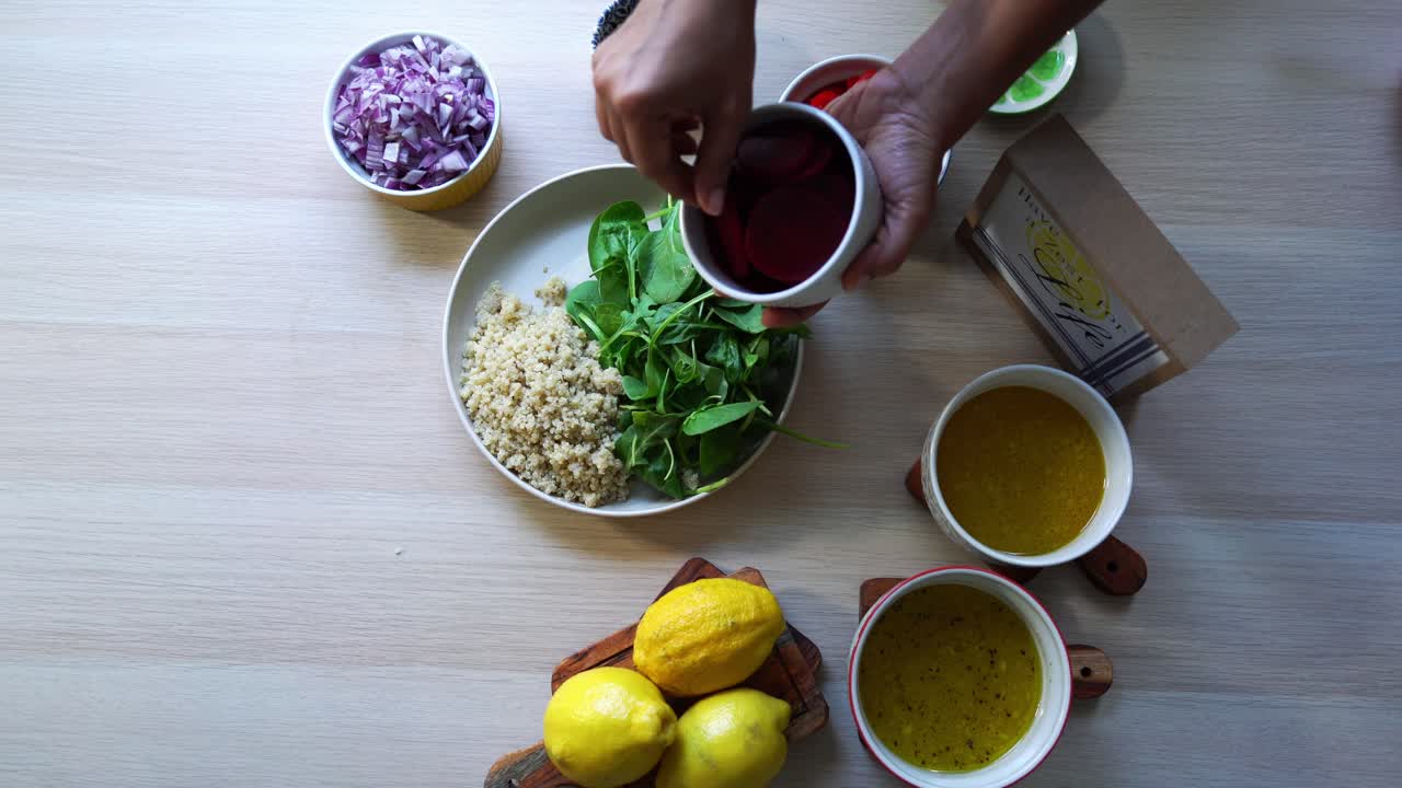 fotografía aérea de la adición de remolachas a la ensalada de quinoa elaboración de una ensalada adición de tomates zanahorias espinacas guisantes limones cebollas nueces aderezo a la vista