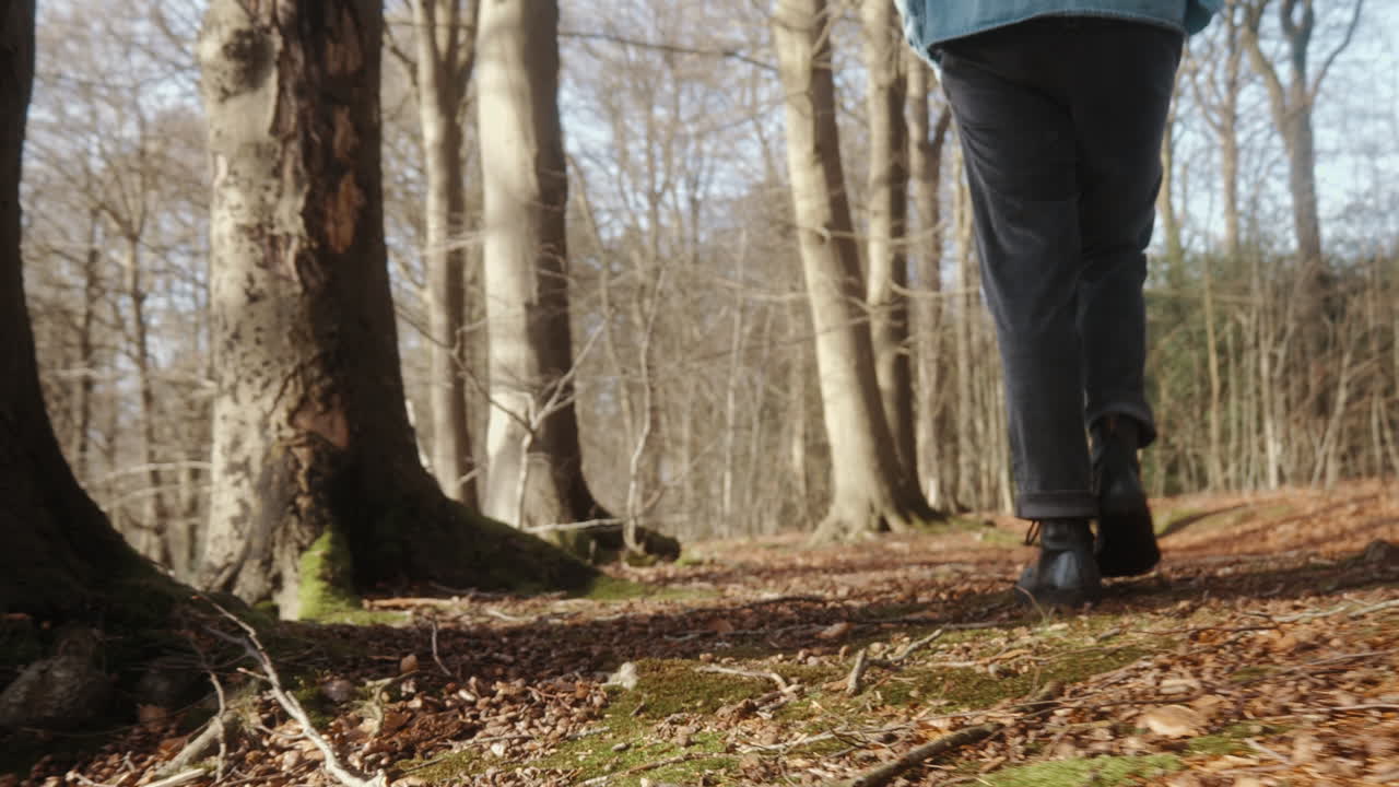 jeune homme marchant sur le sol de la forêt à côté des arbres