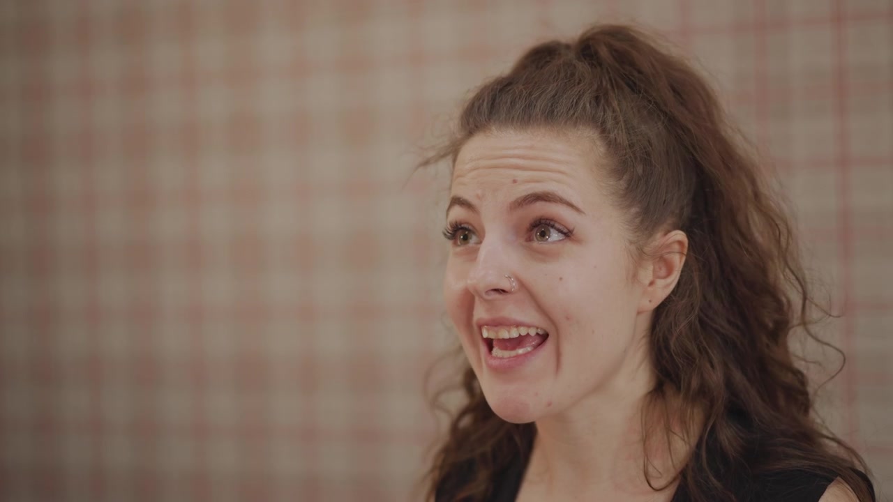 Young caucasian singer practicing warmup exercises in small rehearsal room, closeup facial study, focused breathing and pitch work, subtle smiles and furrowed brow, music teacher watches offframe