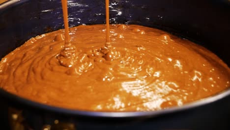 pouring brownie cake dough into steel cooking form for cooking