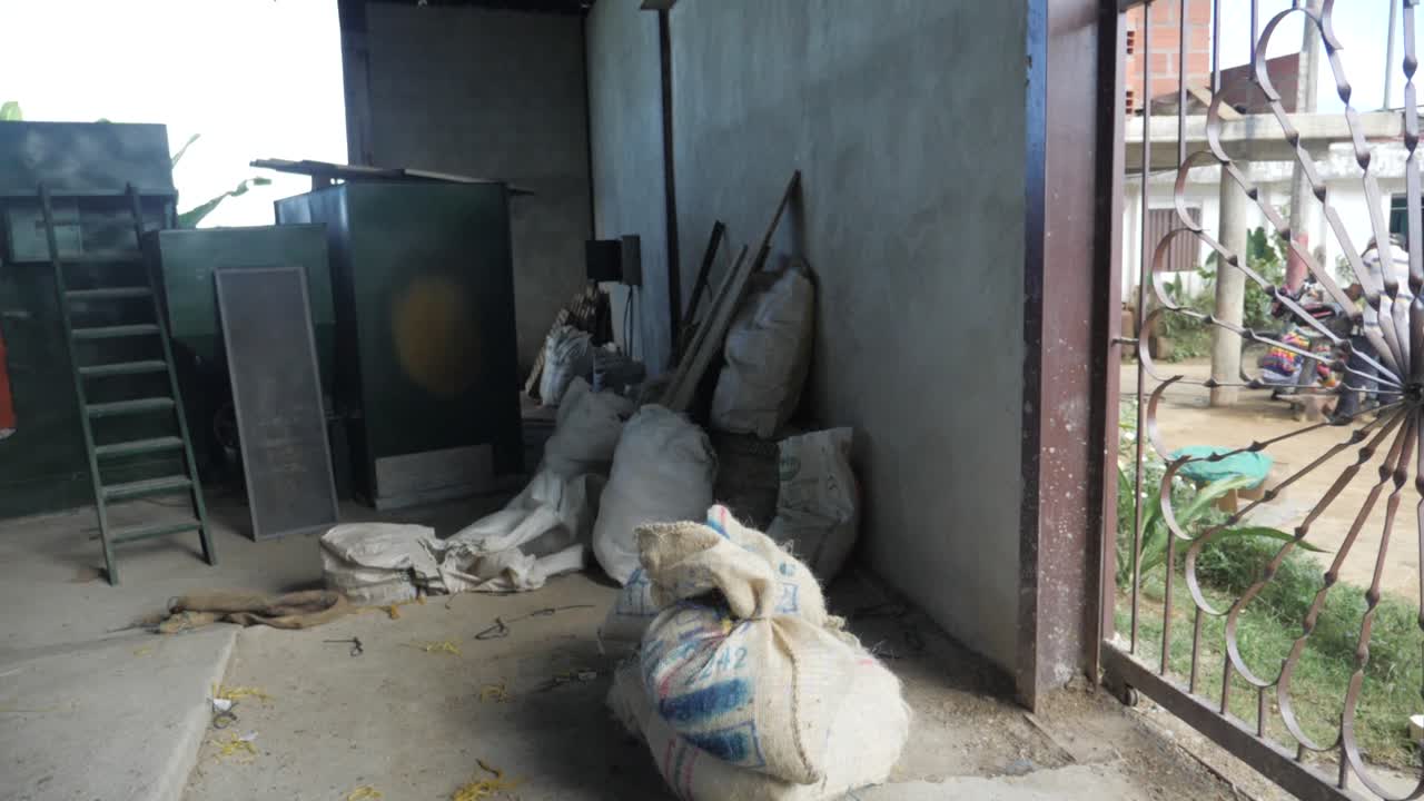 Shot of a coffee plantation where a man carries a heavy bag of raw coffee beans on his shoulder to storage in remote traditional village farmland of Colombia Sierra Nevada slowmotion