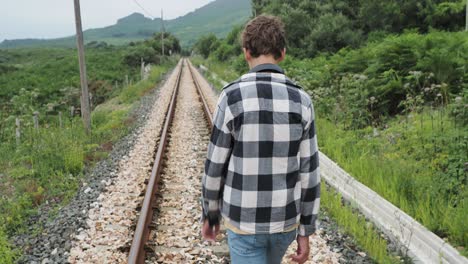 teenager walking away on train tracks