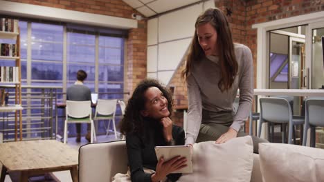 Two-creative-bussinesswoman-discussing-over-digital-table-in-modern-office