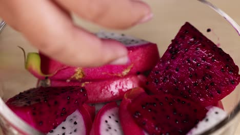 hands preparing dragon fruit slices in bowl