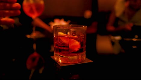 hand holding cocktail glass in dimly lit bar