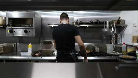 young male chef making very precises movements in commercial kitchen to stay on top of his orders.