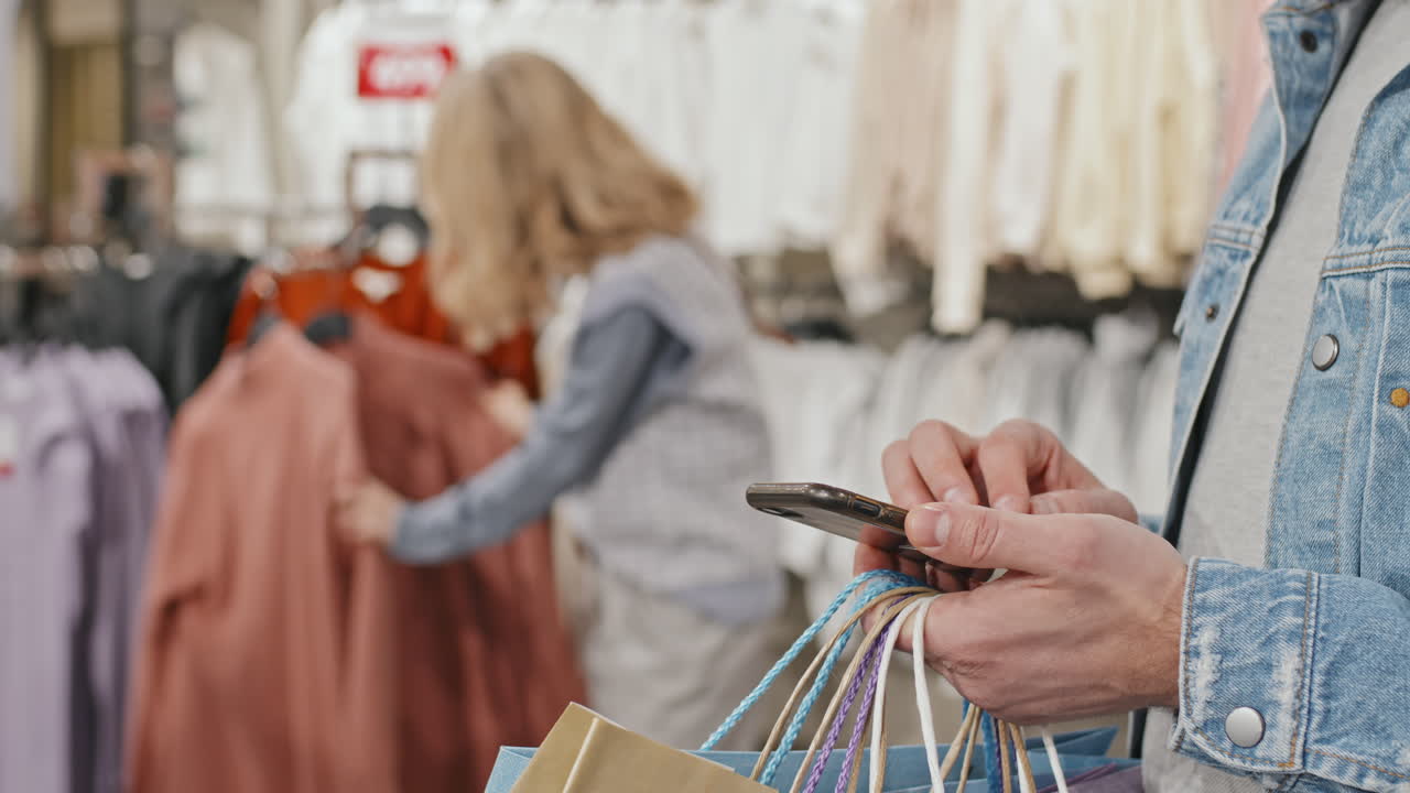 Man With Smartphone During Clothes Shopping With Girlfriend