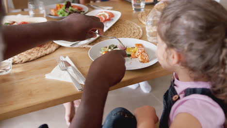 familia de raza mixta de varias generaciones comiendo alrededor de la mesa en casa juntos