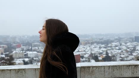 cerca de una atractiva modelo femenina caminando sobre una montaña al lado de la ciudad en invierno