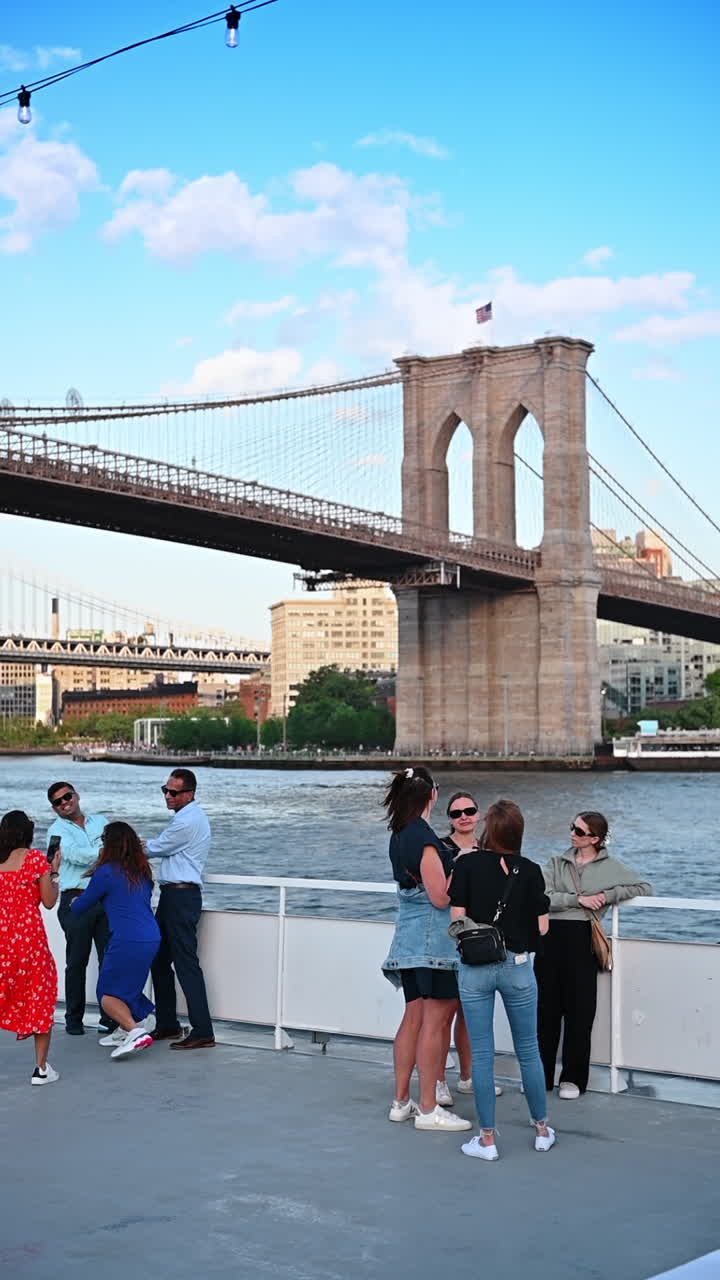 New York, USA, 3 agosto 2025: persone che si godono una crociera al tramonto vicino al ponte di Brooklyn, New York. Gruppo di persone che si godono una crociera sul fiume al tramonto vicino al ponte di Brooklyn.
