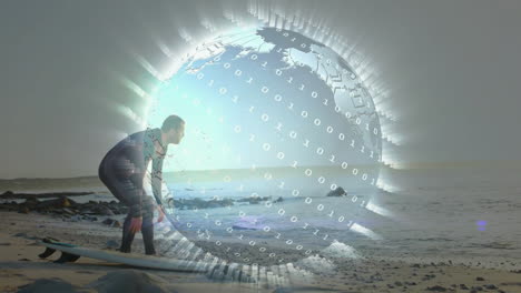 surfer crouching beside surfboard on rocky beach, overlaying tech digital globe with binary code