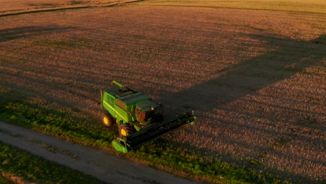 máquina agrícola conduciendo a través del campo, camino por la noche, puesta de sol, caminos visibles fuera de la carretera, campos de cultivo, horizonte