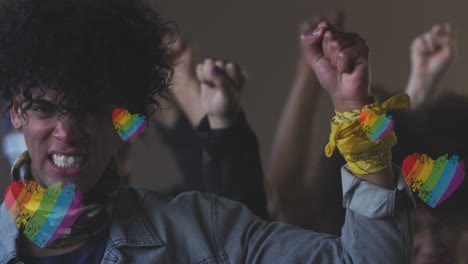 animation of rainbow heart over hands of african american male protester