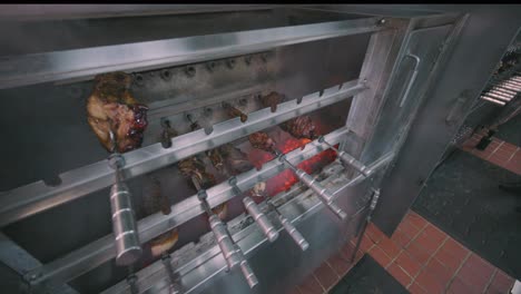 meats being cooked rotisserie style in restaurant oven