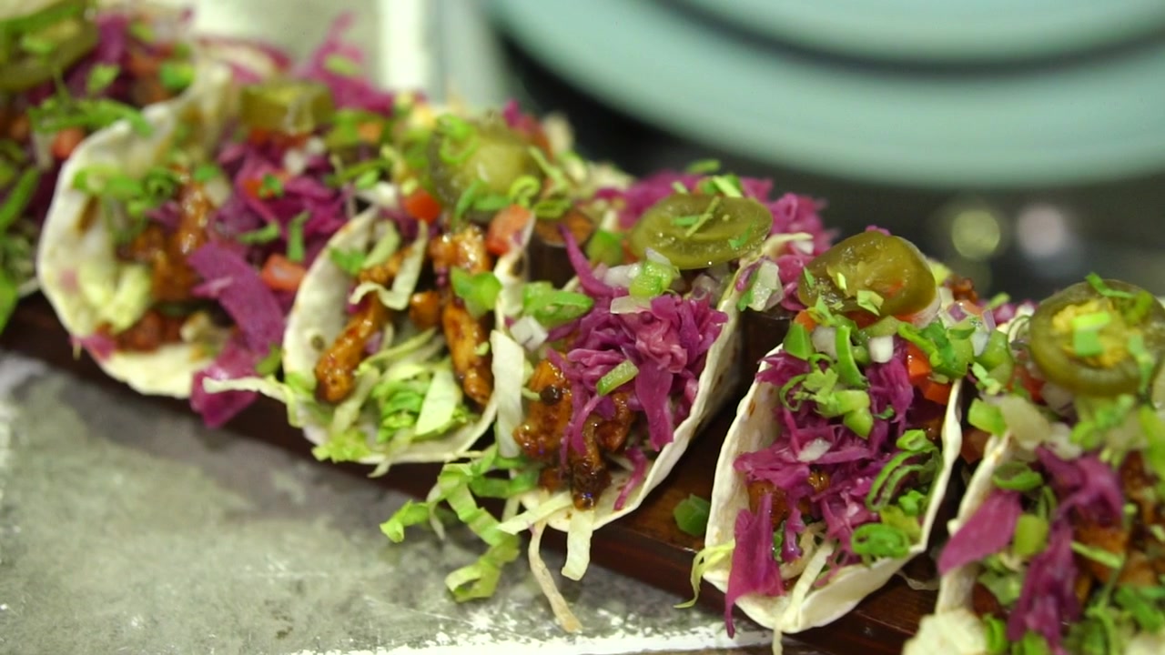 Rækker af burritowraps med kød, bønner og grøntsager på træplade