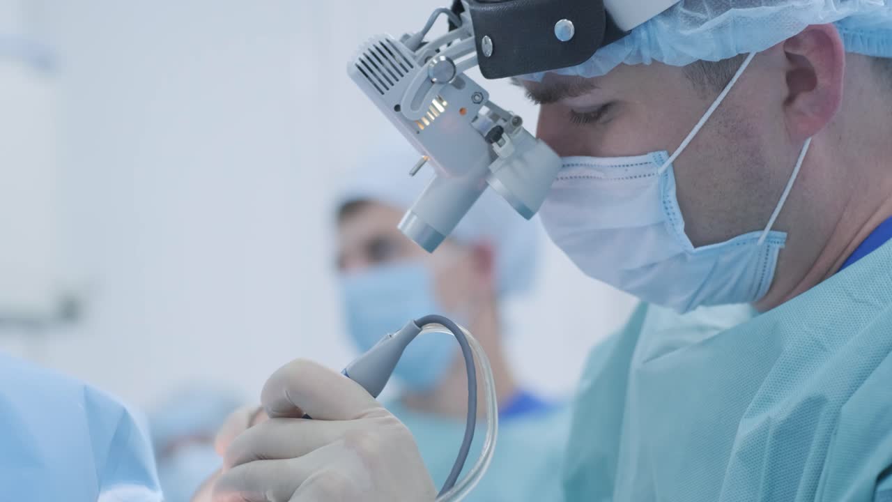 Operation of removing tonsils under deep anesthesia, surgeon uses latest devices, cold plasma method, cuts swelling in throat, doctor works with new probe, medical headlamp, surgical loupes