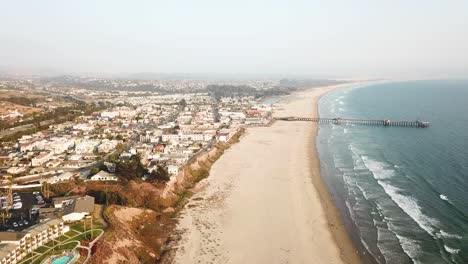 Aerial-forward-over-Pismo-deserted-sandy-beach-and-pier,-California