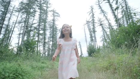 a pregnant woman and her young daughter, both dressed in white, walk hand-in-hand through a grassy park. the scene captures a serene moment of family bonding in nature, surrounded by trees.