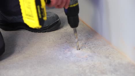 the worker drills holes in the ground with a working electric drill