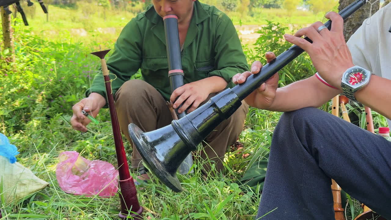 Pemandangan dekat pria lokal memainkan alat musik tiup tradisional di Pasar Minggu Bac Ha, Vietnam, warisan budaya, musik etnik, dan gaya hidup pedesaan.