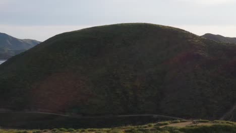 Drohnenschuss,-Der-Während-Der-Kalifornischen-Superblüte-Einen-Wunderschönen-Berggipfel-Umkreist,-Der-Mit-Gelben-Wildblumen-Und-Grünem-Gras-Und-Einem-Großen-Seereservoir-Bedeckt-Ist