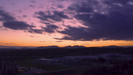 dramatic rolling clouds in sunset time, hyper lapse of sundown above small town with a large factory