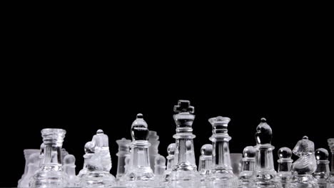 a chessboard with two different full sets of chess pieces made of glass