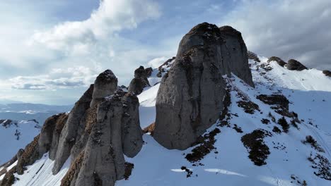 snow-covered ciucas mountains under a blue sky, with rugged peaks and a sense of adventure, aerial shot