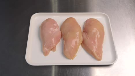 close-up of fresh chicken meat lying on a tray, ready for further processing