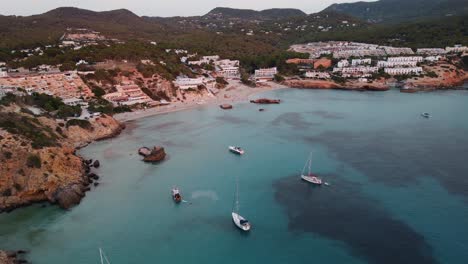 Atemberaubende-Luftaufnahme-Der-Küste-Von-Cala-Tarida-Mit-Im-Wasser-Festgemachten-Booten