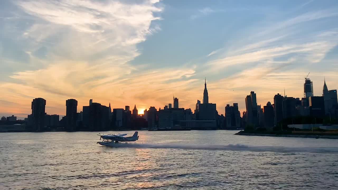 Idrovolante che decolla con Manhattan sullo sfondo al tramonto.