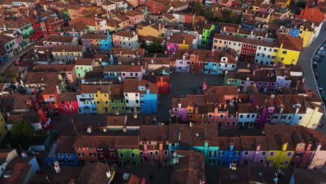 brightly painted facade of houses in burano island at sunset in venice, italy. - aerial shot