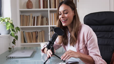 woman recording podcast at home office with microphone and laptop nearby