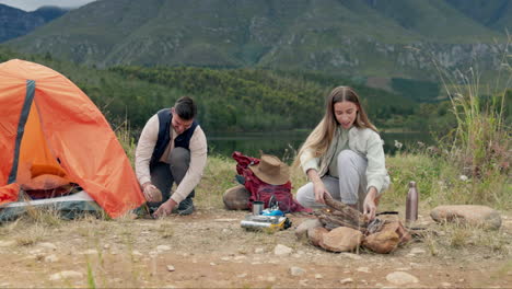 Couple,-campfire-and-set-up-tent-in-nature