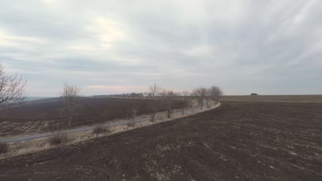 flying towards asphalt road in remote farmland against cloudy sky