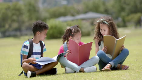 biracial boy and two biracial girls are engrossed in reading books outdoors in school