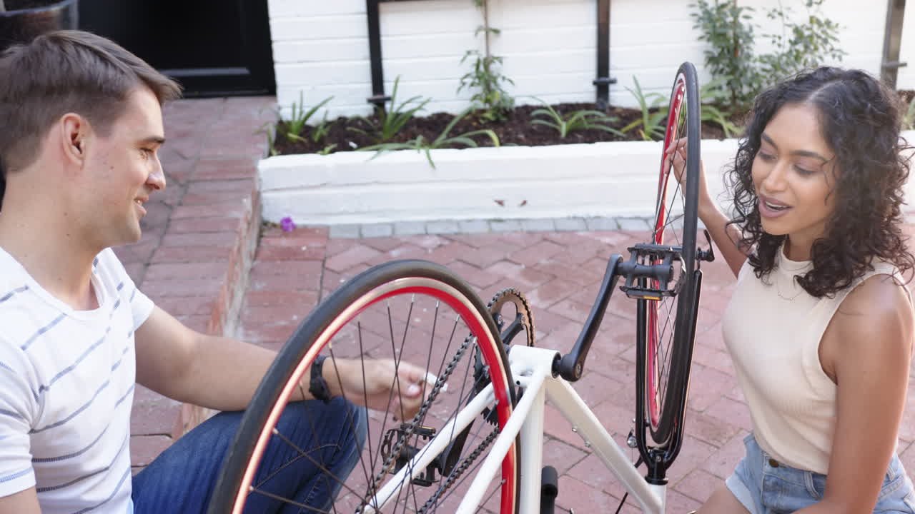 Repairing bicycle together, young multiracial couple working on bike maintenance outdoors