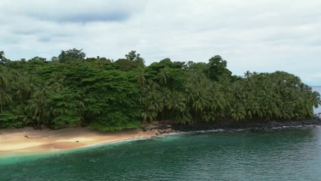 Aerial-view-of-turquoise-water-beach-surrounded-by-lush-tropical-jungle-in-Principe-Island