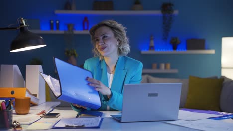 una trabajadora de oficina en casa mirando archivos de papeleo.